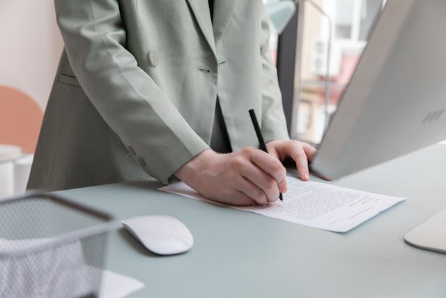 person%20in%20a%20mint%20green%20jacket%20signing%20a%20document person%20in%20a%20mint%20green%20jacket%20signing%20a%20document